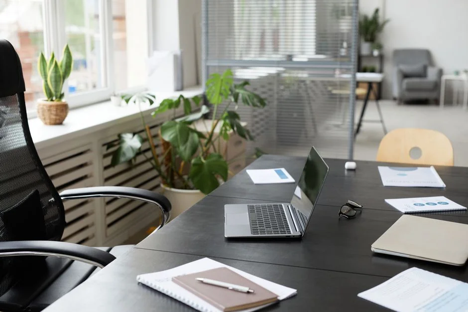 A tidy home office space featuring a wooden desk, chair, broom, and cleaning equipment.